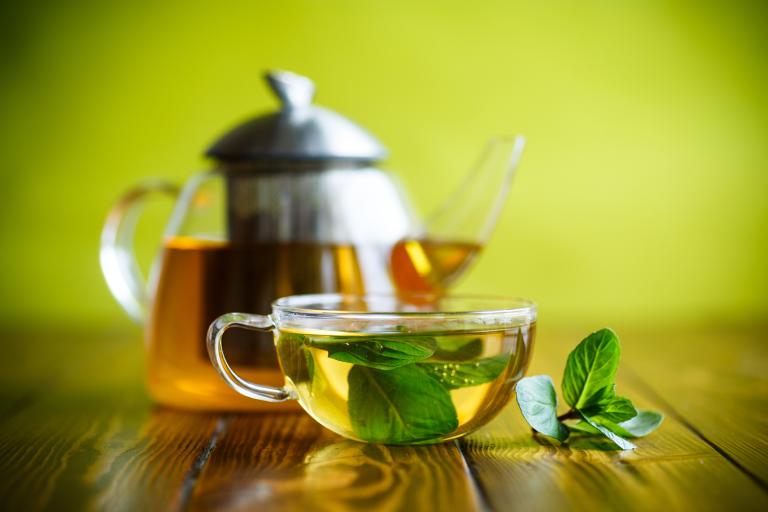 a kettle and cup of loose-leaf green tea