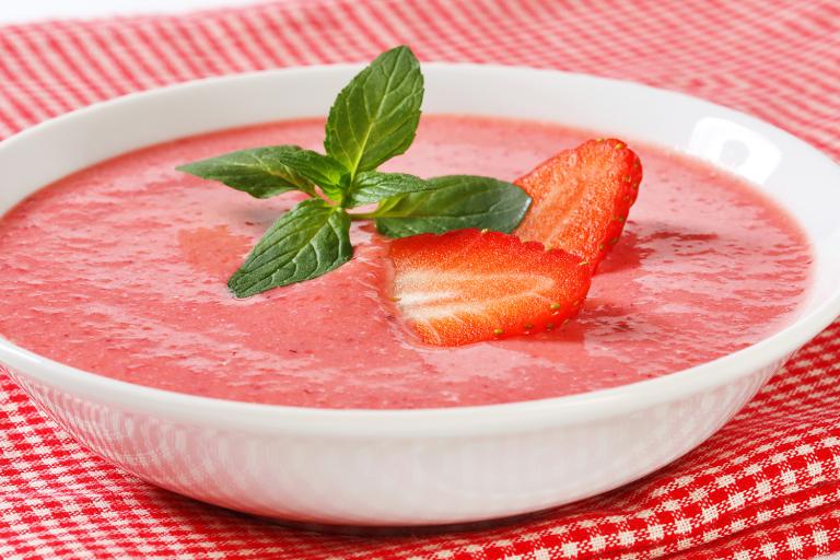 a cold bowl of creamy strawberry soup garnished with mint