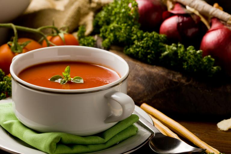 a bowl of soup surrounded by fresh vegetables